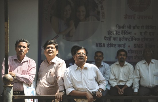 Bystanders watch share prices displayed on a digital broadcast on the facade of the Bombay Stock Exchange building in Mumbai. The 30-stock Sensex closed down 0.5% yesterday, after changing direction at least 15 times.