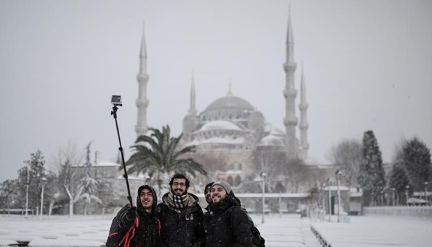 People pose for a selfie during a snowfall in Istanbul on Thursday. Istanbul had a thick covering of snow by early today, while almost 30 centimetres fell in some parts of the city, causing disruptions to transport services and the closure of several roads.