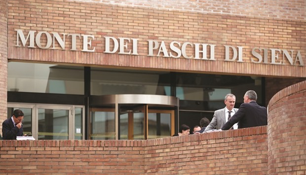 Pedestrians stand outside the administrative offices of Monte dei Paschi in Siena, Italy. Milan shares ended 0.7% lower, dragged down by Monte dei Paschi di Siena, whose stock tumbled over 10%.