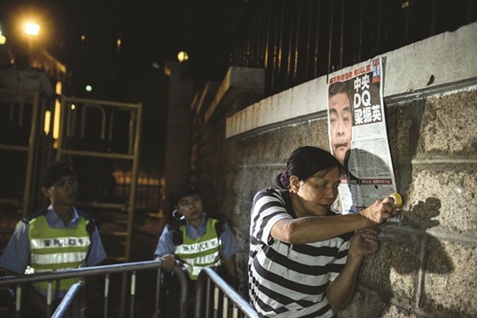 A pro-democracy protester posts a newspaper page featuring unpopular chief executive Leung Chun-Ying during a rally outside his residence in Hong Kong yesterday.