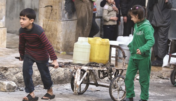 A boy pushes a cart with water containers in a rebel-held besieged area of Aleppo, Syria, yesterday.