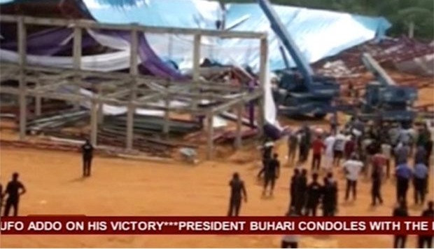 People stand near the remains of a church which collapsed during a service in the southern city of Uyo in Akwa Ibom state, Nigeria in this still image from video.