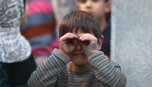 A boy reacts to a photographer while waiting to fill containers with water in a rebel-held besieged area of Aleppo on Saturday.