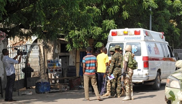Emergency services and soldiers gather at the scene of a suicide bomb attack on a market in Maiduguri, after two girls approximately seven or eight years old blew themselves, killing themselves and wounding at least 17 others.
