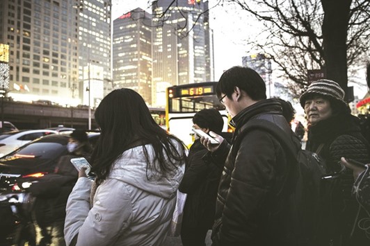 Commuters using smartphones stand in line at a bus station in Beijing. Chinau2019s battle for recognition as a market economy that would help it avoid penalties from key trade partners has been thwarted, as a key clause in Beijingu2019s deal to join the WTO expired yesterday.