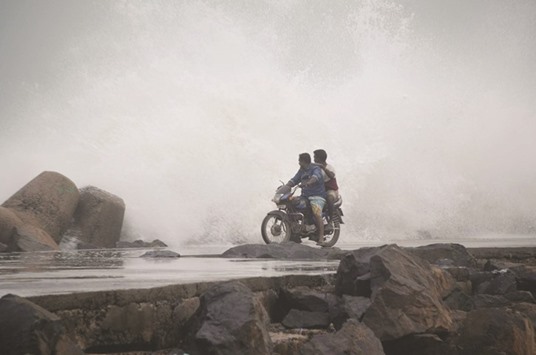 Two men look on as high waves hit the shore in Chennai yesterday. The weather office called yesterday for fishermen to stay ashore hours before a very severe cyclone storm is due to strike the southeast coast, including Chennai.