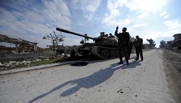 Forces loyal to Syria's President Bashar al-Assad walk past a tank in the government held Sheikh Saeed district of Aleppo
