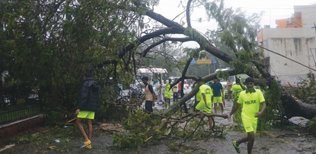 Rescue workers walk along a street strewn with debris and fallen trees in Chennai yesterday. The authorities shifted thousands of people to relief centres.