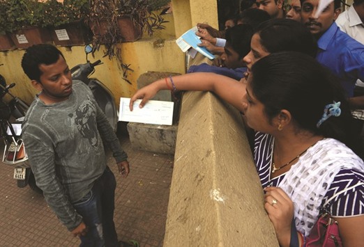 Bank customers try to hand over cheques to a member of staff outside a bank in Mumbai yesterday.