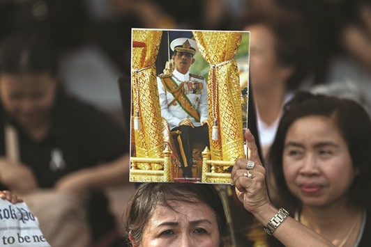 A woman holds up a picture of Thailandu2019s Crown Prince Maha Vajiralongkorn ahead of his arrival at the Grand Palace in Bangkok.