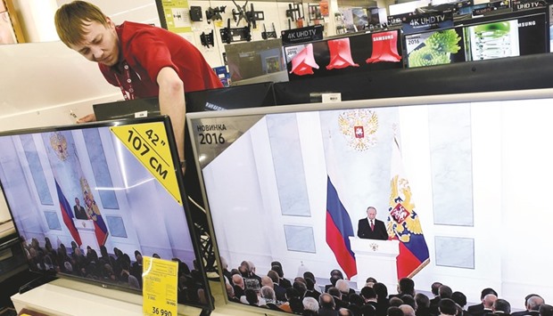 A shop assistant at an electronics store in Moscow works behind TV sets broadcasting Putinu2019s state of the nation address at the Federal Assembly.