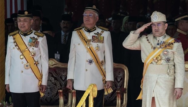 Sultan Muhammad V (right), the incoming 15th king of Malaysia, saltues as Malaysian Prime Minister Najib Razak (centre) and his deputy Ahmad Zahid Hamidi stand during the king's welcoming ceremony at Parliment House in Kuala Lumpur on Tuesday.