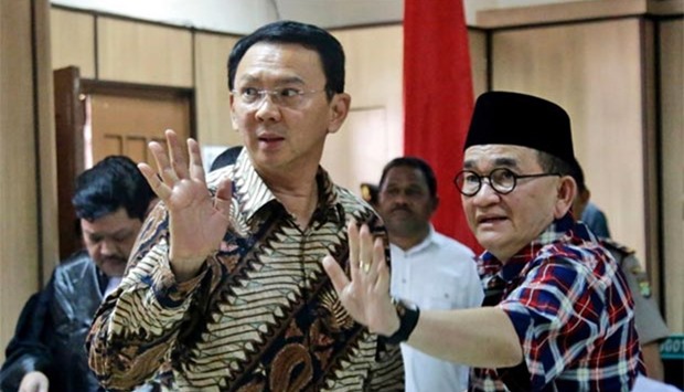 Jakarta Governor Basuki Tjahaja Purnama (left) and his campaign spokesman Ruhut Sitompul wave to photographers after his trial for blasphemy at the North Jakarta District Court in Jakarta on Tuesday.