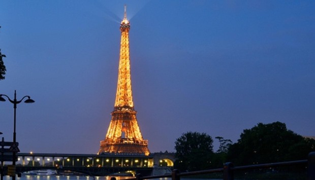 The lighted Eiffel Tower in front of the Seine river in front Beaugrenelle in Paris