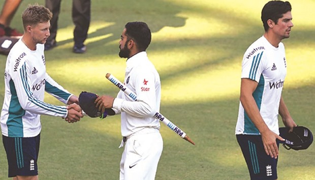 England captain Alastair Cook walks off as India captain Virat Kohli (centre) greets Cooku2019s deputy Joe Root after India won the fourth Test in Mumbai on Monday. (AFP)
