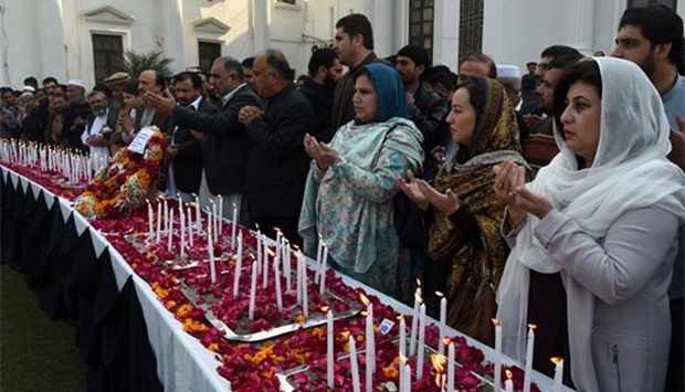 Pakistani legislators pray beside lighted candles as they pay tribute to victims on the second anniversary of an attack on the Army Public School in Peshawar on Friday.