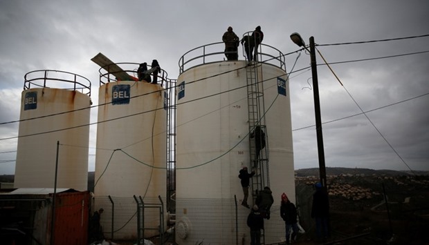 Israeli youths climb atop water tanks as they make preparations for an expected eviction in the Jewish settler outpost of Amona in the West Bank.