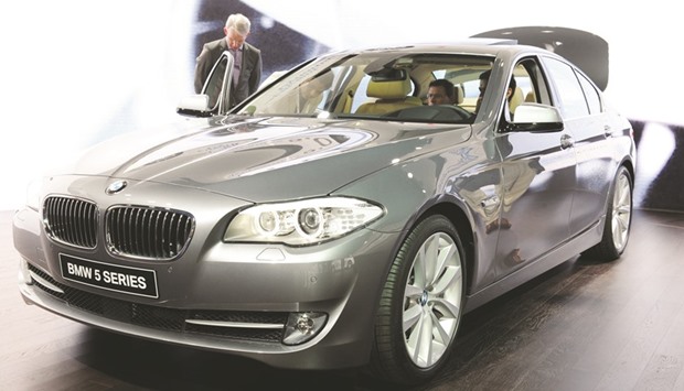 A visitor looks at a BMW 5-Series automobile on display at the Geneva International Motor Show (file). BMWu2019s growth next year hinges on the revamped 5-Series, which was officially unveiled in Lisbon recently and generates as much as a fifth of its automotive profit.