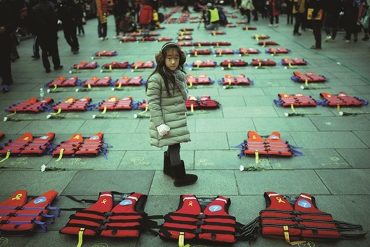 A girl stands between life vests symbolising the 304 victims of sunken ferry Sewol during a protest in Seoul demanding President Parku2019s resignation.