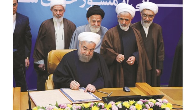 Iranian President Hassan Rouhani signs documents as part of the landmark bill of rights that he unveiled, during a televised ceremony in Tehran yesterday.