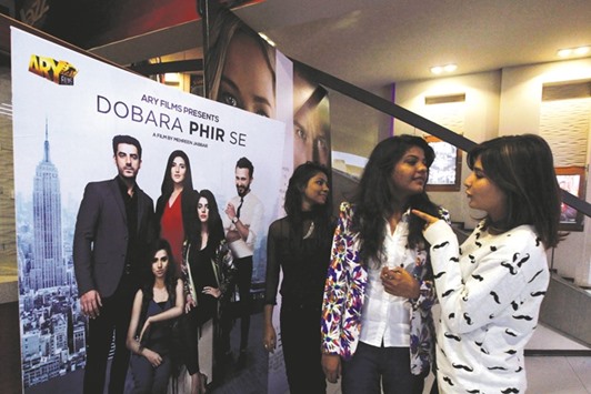 Women chat as they stand near a poster of Pakistani film Dobara Phir Se at Atrium Mall & Cinemas in Karachi, Pakistan, on Monday.