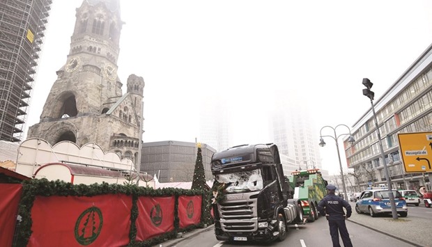 The truck used in the attack on the Christmas market near the Kaiser-Wilhelm-Gedaechtniskirche (Kaiser Wilhelm Memorial Church) in Berlin is towed away yesterday as forensic experts examine the scene around the vehicle.
