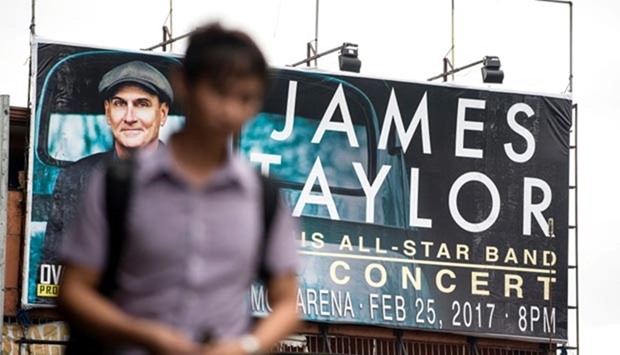 A man walks past a billboard promoting a planned concert by US singer James Taylor in Manila on Wednesday.