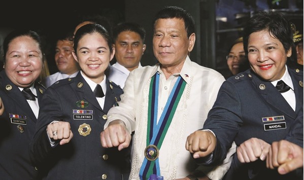 President Rodrigo Duterte gestures his election campaign fist bump with female military officers during the Armed Forces anniversary celebration at Camp Aguinaldo in Quezon city, Metro Manila.