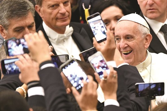 Pope Francis, right, arrives to lead his weekly general audience at Paul VI hall yesterday at the Vatican as people take pictures of him with their cell-phone.