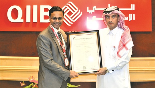 Al-Jamal (right) receives the certificate of compliance from Shanthamurthy at a function held at the QIIB headquartersu2019 in Doha recently.