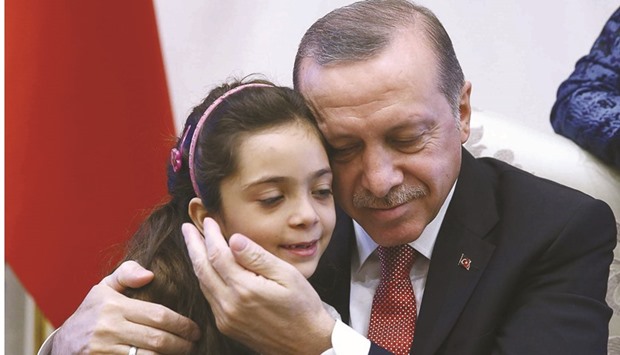 Turkeyu2019s President Recep Tayyip Erdogan holds in his arms the seven-year-old Bana Alabed, who tweeted from Aleppo on the attacks, at the Presidential Complex in Ankara.