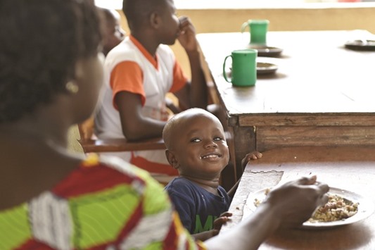 A child grins at his nanny while having a meal at the Saint Genevieve  Welcome and Transit Centre for so-called u2018cursed childrenu2019.