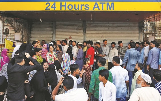 People queue outside a bank to withdraw cash and deposit their old high denomination banknotes in Mumbai yesterday.