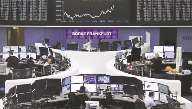 Traders work at their desks in front of the DAX board inside the Frankfurt Stock Exchange yesterday. The Dax 30 index slipped 0.2% down at 10,513.35 points at close.
