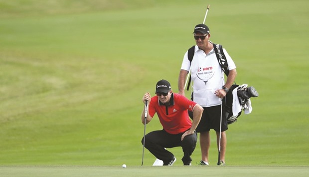 Justin Rose of England lines up his putt on the ninth green with caddie mark Fulcher during round one of the Hero World Challenge at Albany, The Bahamas, on Thursday.