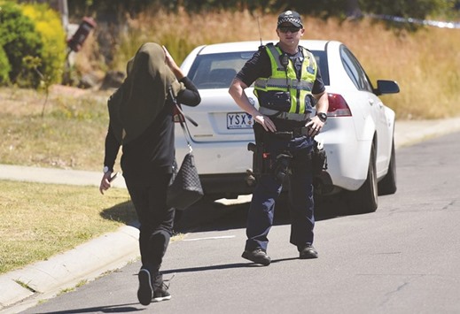 A woman approaches a policeman as he blocks the road during the search of a house in the Meadow Heights of Melbourne, Australia, during an anti-terror operation yesterday.