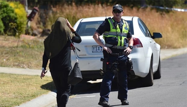 A woman approaches a policeman as he blocks the road during the search of a house in the Melbourne suburb of Meadow Heights on Friday.
