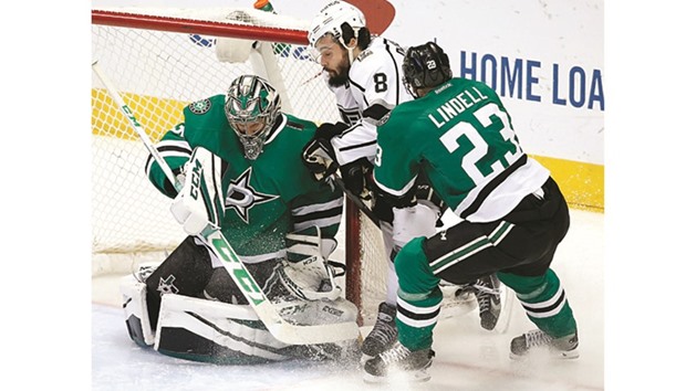 Dallas Stars goalie Kari Lehtonen (L) saves a shot by the Los Angeles Kingsu2019 Drew Doughty (C), who collides with the goal after being pushed by Stars defenseman Esa Lindell.