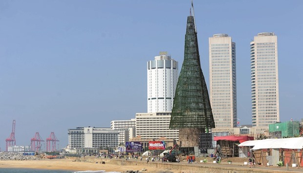 Pedestrians walk past a partially-constructed Christmas tree in Colombo yesterday.