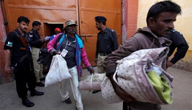 Indian fishermen walk out from a prison with their belongings after they were released in Karachi on Sunday.