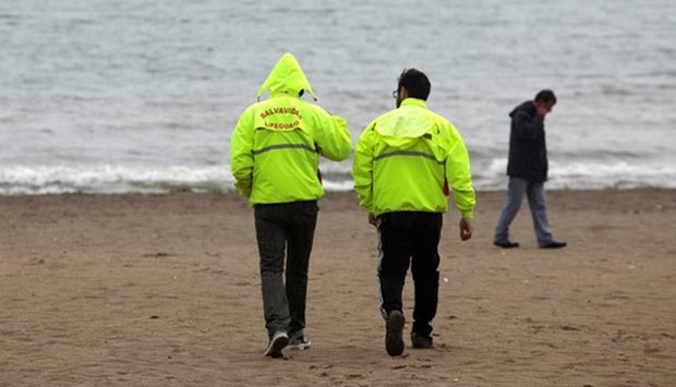 Lifeguards walk on an evacuated beach in Penco town during a tsunami alert after a quake hit Chiloe island, southern Chile, on Sunday.