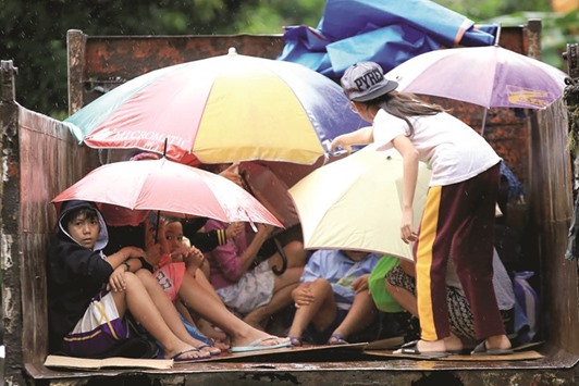 Young residents sit in a truck after the local government implemented pre-emptive evacuations at Barangay Matnog province yesterday, due to the approaching typhoon Nock-Ten.