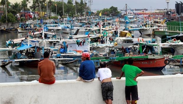 Residents look at fishermen as they secure their fishing boats to avoid typhoon Nock-Ten at a port in Manila on Monday.
