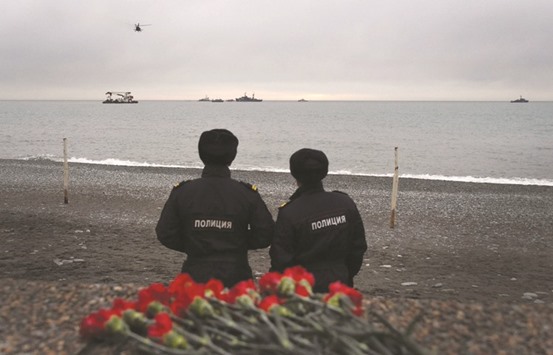 Police officers look at rescue vessels searching the Black Sea outside Sochi, two days after a military plane carrying 92 people crashed into the waters.