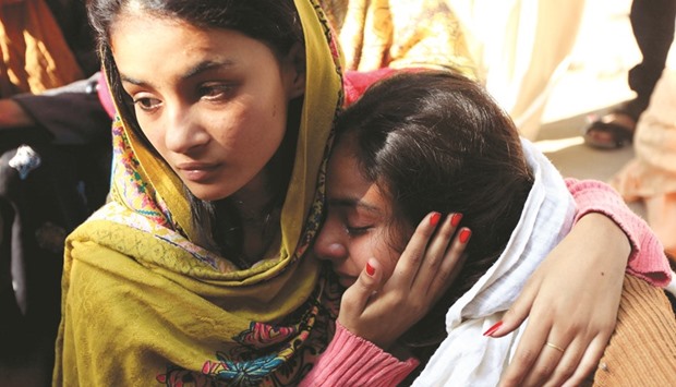A woman is comforted as she mourns the death of a relative, who died after consuming locally made toxic liquor, in Toba Tek Singh, Pakistan, yesterday.