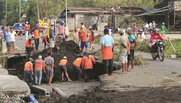 Workers inspect a road damaged by the  typhoon in Tabaco, Albay province yesterday.
