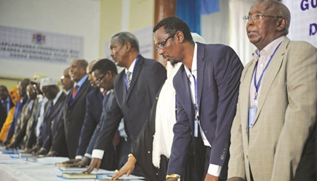 Members of Somaliau2019s new federal parliament place their hands on copies of the Quru2019an during their swearing-in ceremony at the General Kahiye Academy in Mogadishu.