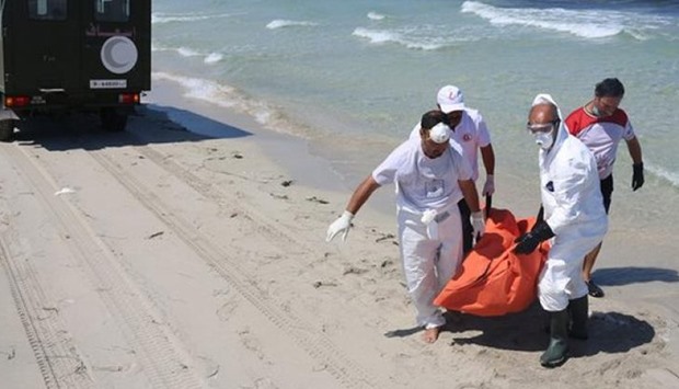 Workers carry a body that was washed up on shore