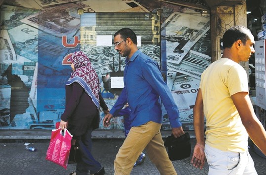 People walk past an exchange bureau with an advertisement showing images of the US dollar and other foreign currency in Cairo. Officials say floating the pound was a necessary measure to restore investor confidence and end a dollar shortage that has hammered businesses. It enabled the government to secure a $12bn loan from the IMF as it tries to attract foreign capital and revive economic growth.