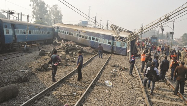 Rescuers and railway officials stand next to damaged coaches of a passenger train after it derailed near Kanpur in Uttar Pradesh yesterday.